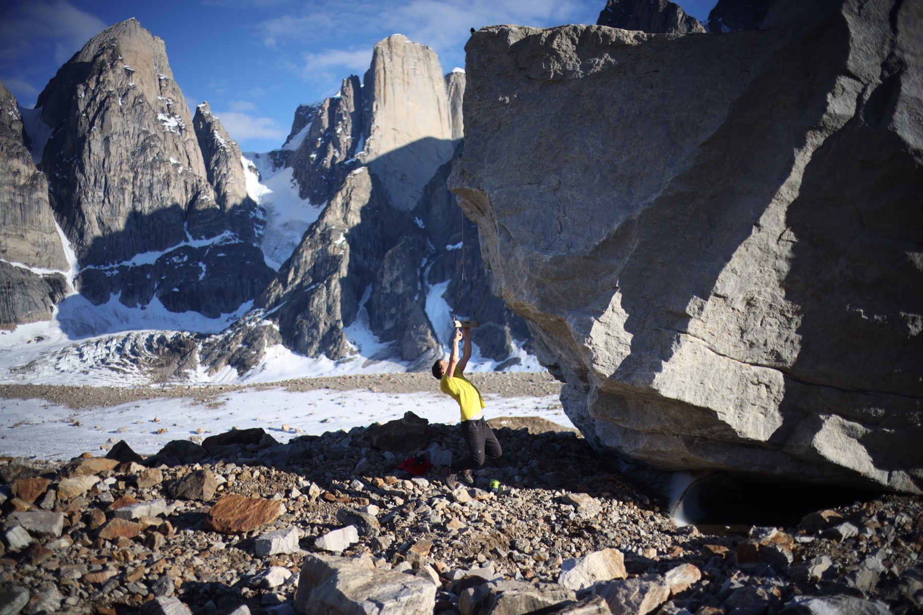 A climber beneath an overhanging boulder in Greenland
