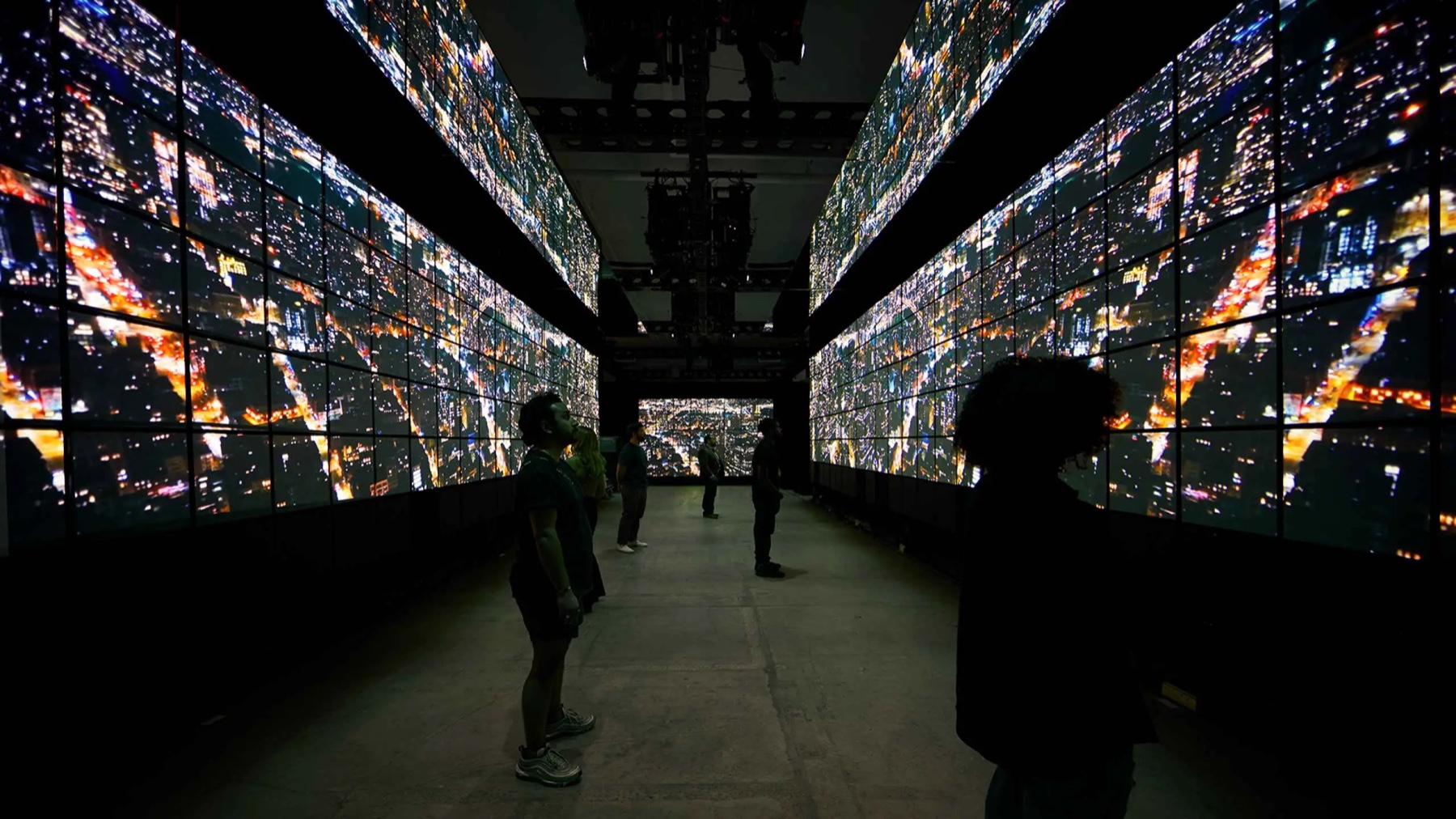Visitors surrounded by nighttime images of New York across the installation's screens