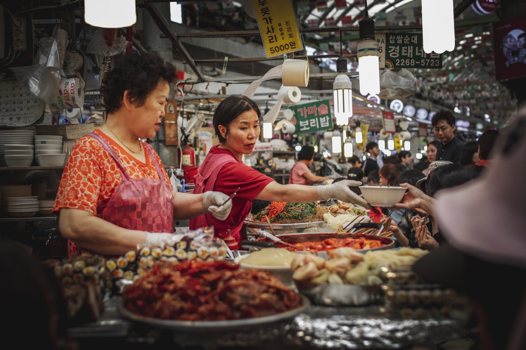 Vendors serving food in a busy Seoul market