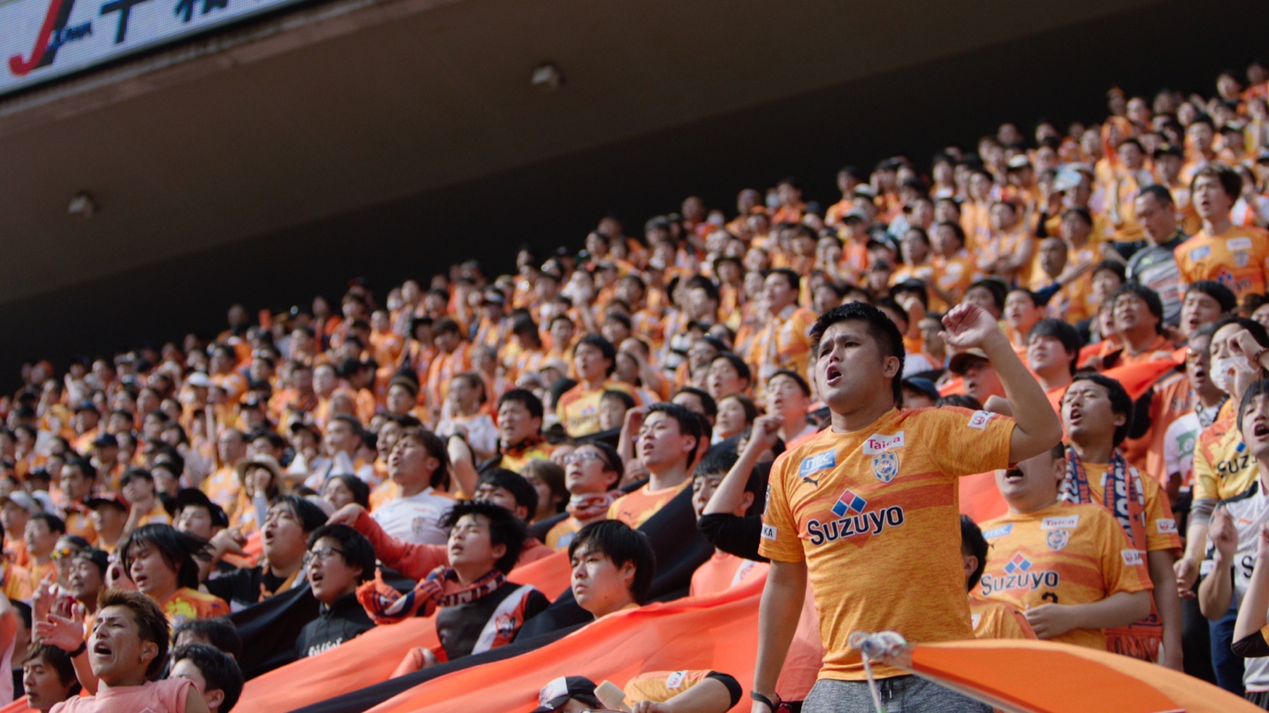 Football supporters singing in a packed stadium