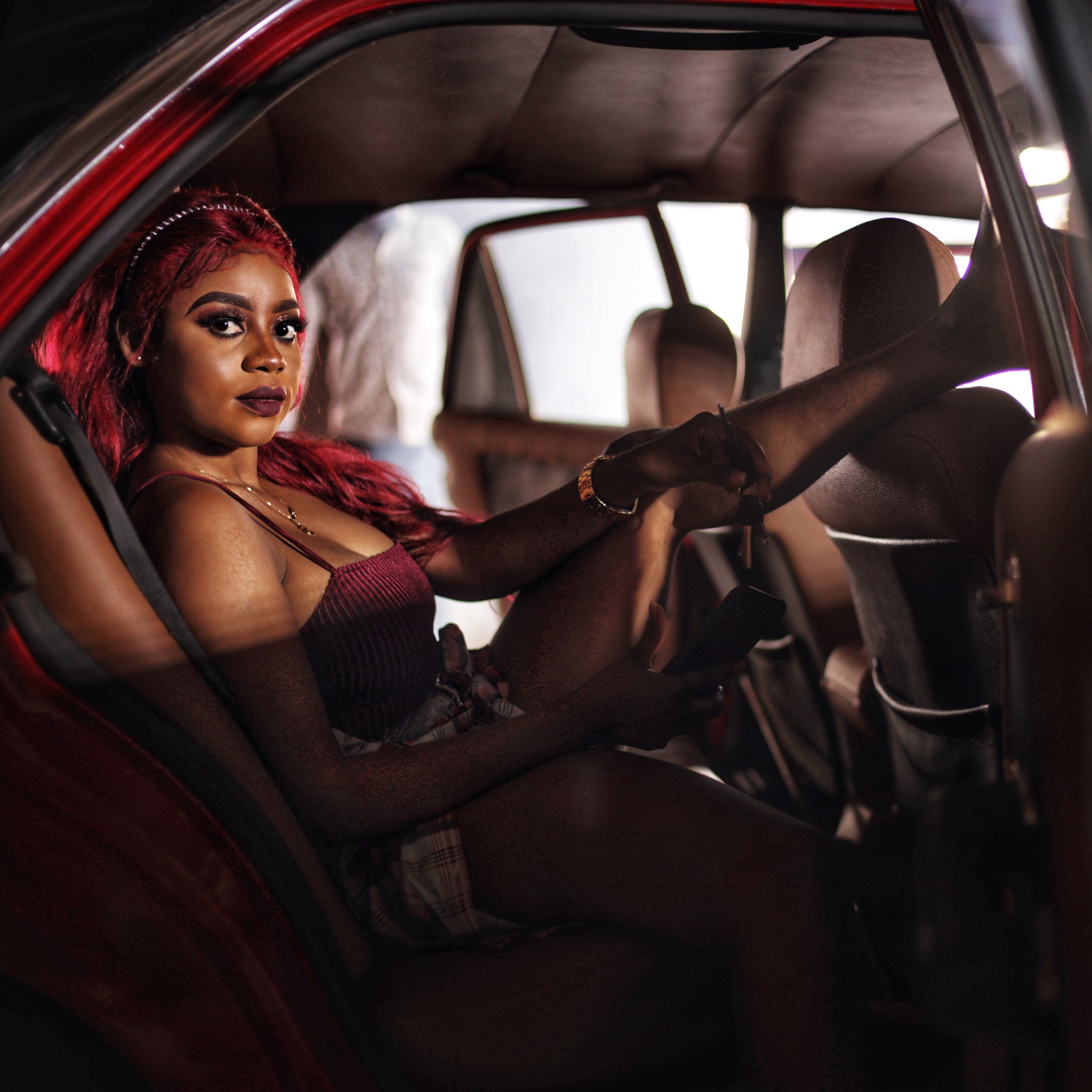 A woman photographed inside a car under red light