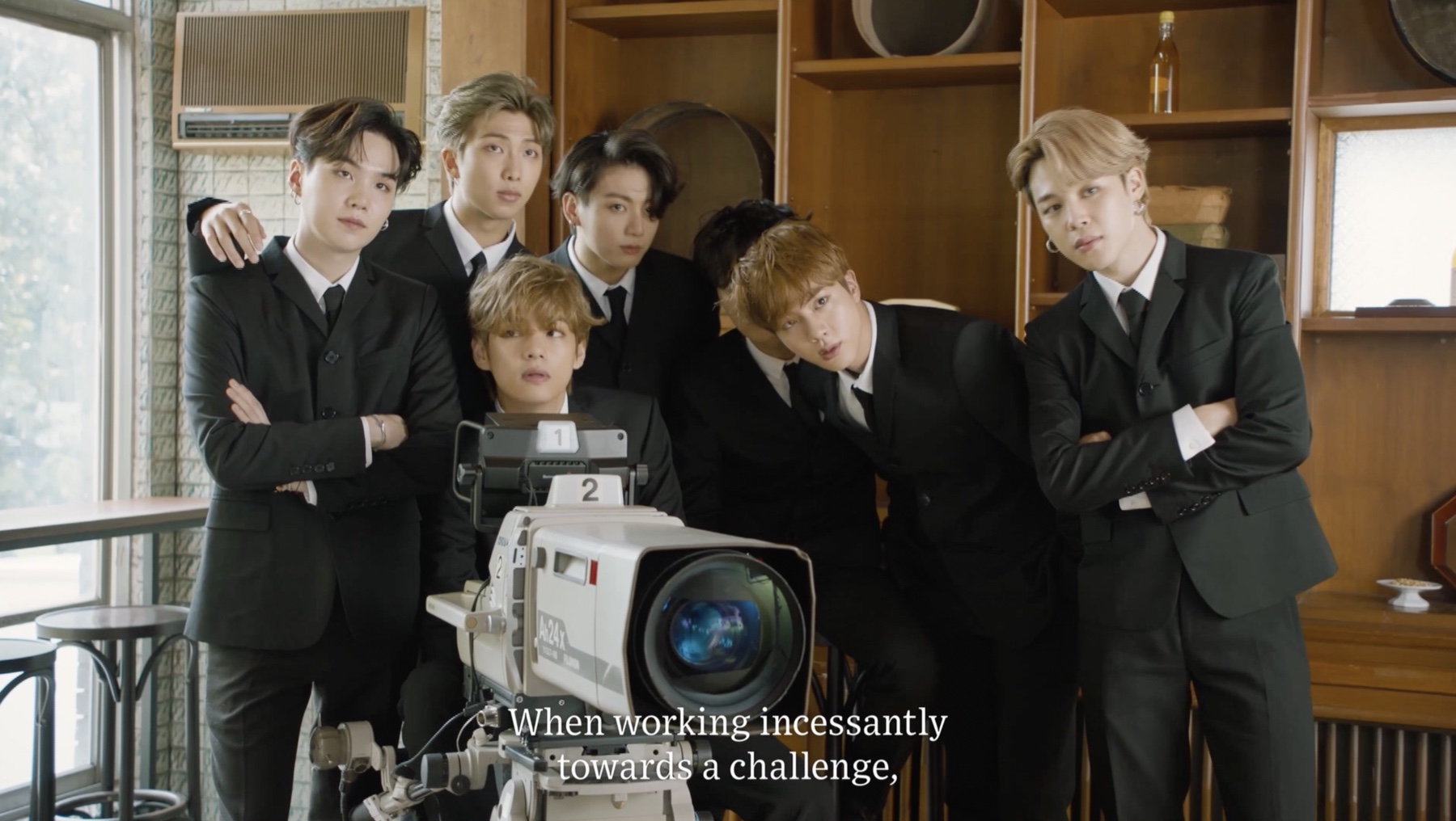 BTS gathered around a vintage television camera